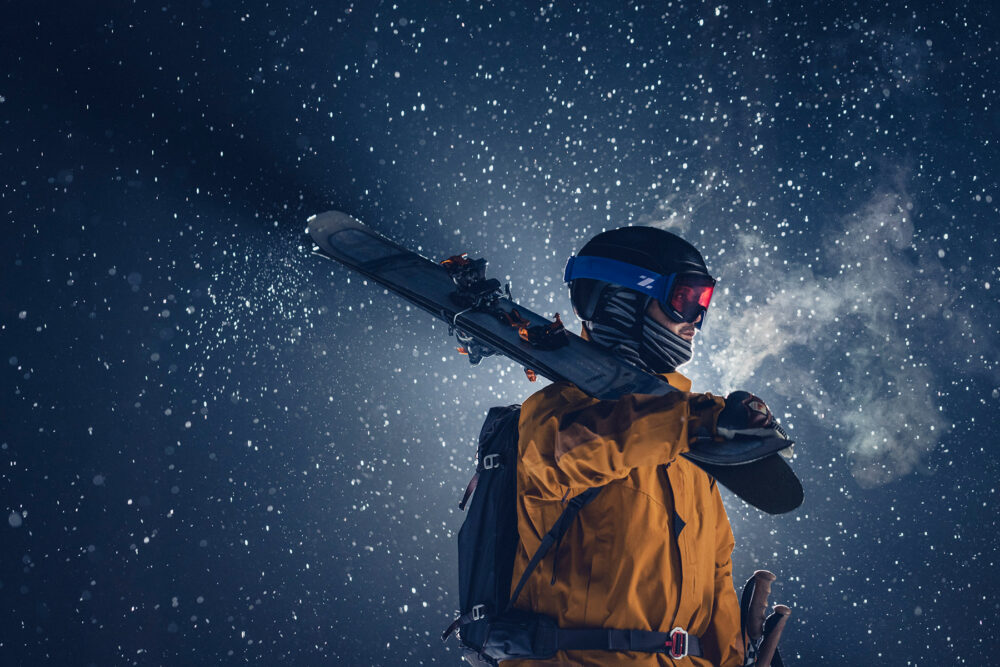 Man standing with his skis on his shoulder